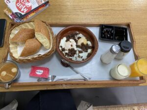 Tadżin śniadaniowy podany z mięsem, chlebem i oliwkami.