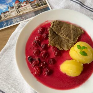 Wołowina w sosie wiśniowym - przepis na soczyste mięso w aromatycznym, słodko-kwaśnym sosie wiśniowym, podane elegancko na talerzu z ziołami i świeżymi wiśniami.