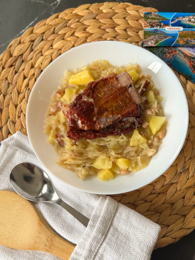 Istarska jota to esencja zimowego comfort foodu: aromatyczna kapusta kiszona, miękkie ziemniaki i sycąca fasola tworzą gęstą, rozgrzewającą zupę z charakterem. Całość dopełniają żeberka i boczek, które nadają jej głębi i wyrazistości. Poznaj prosty przepis na chorwacki kapuśniak, który smakuje domowo, treściwie i kojąco.